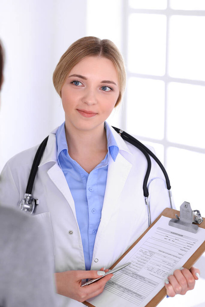 Young woman doctor and patient at medical examination at hospital office. Blue color blouse of therapist looks good. Medicine and healthcare concept - Foto, Imagem