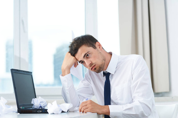 Молодий сумний бізнесмен в офісі з ноутбуком
 - Фото, зображення