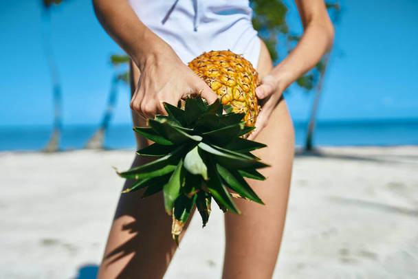 Uma mulher de fato de banho branco com ananás. Foto de alta qualidade - Foto, Imagem