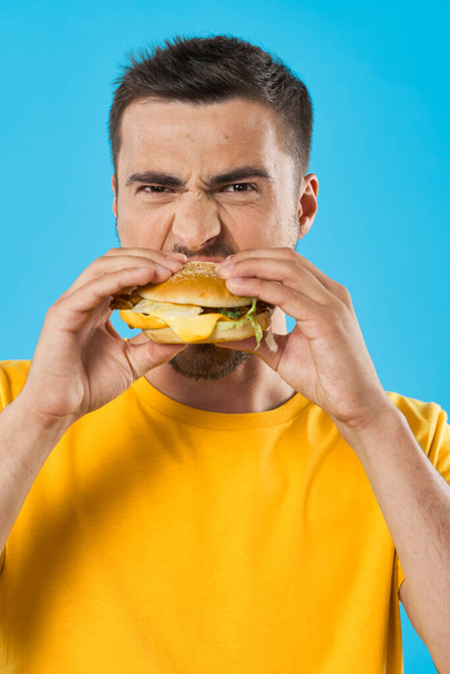Jeune homme avec hamburger en studio  - Photo, image