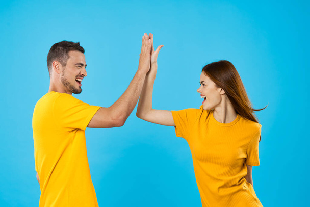 young woman and man giving high five on blue background  - Zdjęcie, obraz