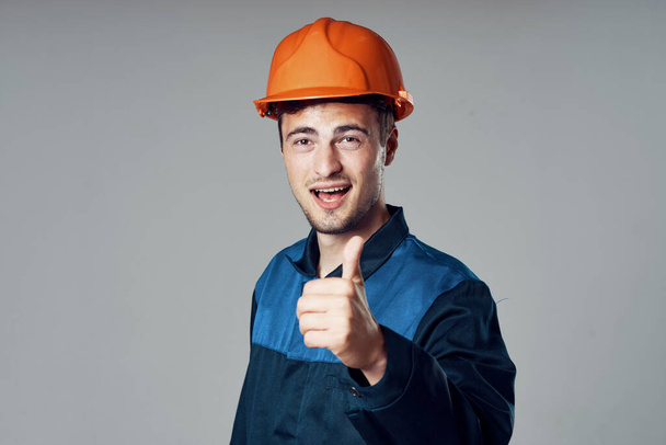 Studioaufnahmen. Industriearbeiter mit orangefarbenem Helm mit erhobenem Daumen - Foto, Bild