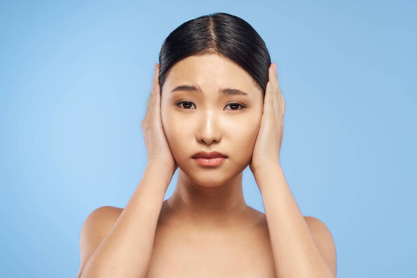 Portrait de belle femme asiatique couvrant les oreilles sur fond isolé  - Photo, image