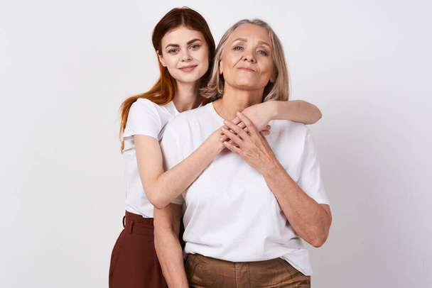 νεαρή γυναίκα με τη μητέρα της να αγκαλιάζεται στο στούντιο    - Φωτογραφία, εικόνα