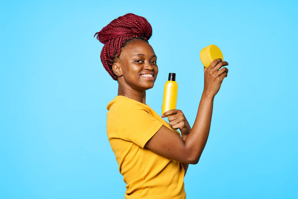  donna di aspetto africano che presenta cosmetici su sfondo isolato - Foto, immagini