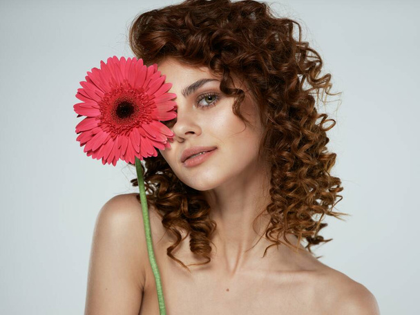 Young woman with flower posing in studio - Фото, зображення
