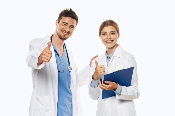 Jonge arts en verpleegkundige met duimen omhoog in de studio, geïsoleerde achtergrond.  - Foto, afbeelding