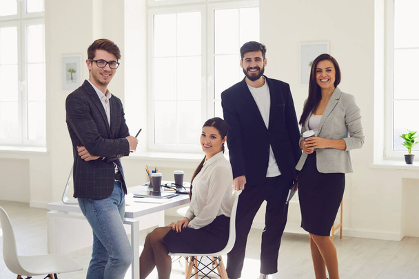 Group of business people standing looking smiling standing at a table in the office - Фото, изображение