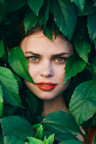 Joven hermosa mujer posando con hojas alrededor de su cara
 - Foto, Imagen