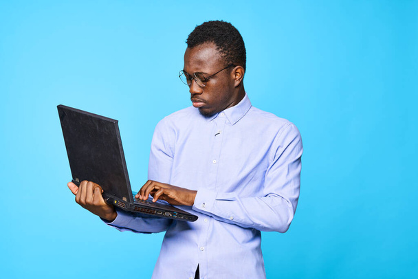 Молодий африканський бізнесмен тримає ноутбук ізольований на синьому фоні
 - Фото, зображення