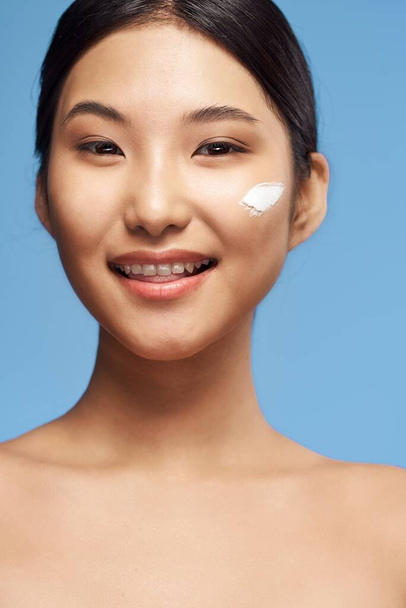 若いですアジアの女性適用保湿剤オン彼女の顔  - 写真・画像