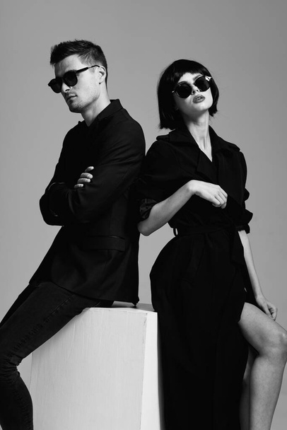 Νεαρό όμορφο ζευγάρι με γυαλιά ηλίου που ποζάρει στο στούντιο. Μαύρο και άσπρο.    - Φωτογραφία, εικόνα