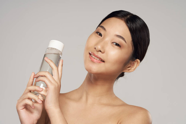 Студийный снимок Портрет молодой азиатки с косметическим продуктом
 - Фото, изображение