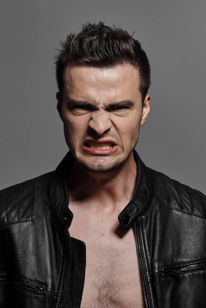 young handsome  angry man  on dark background. Studio shot   - Photo, Image