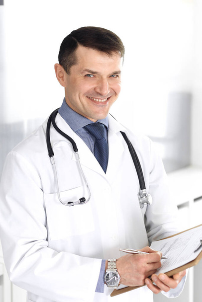 Doctor man using clipboard for filling up medication history records. Perfect medical service in clinic. Physician at work in hospital. Medicine and healthcare concepts - Foto, Imagem