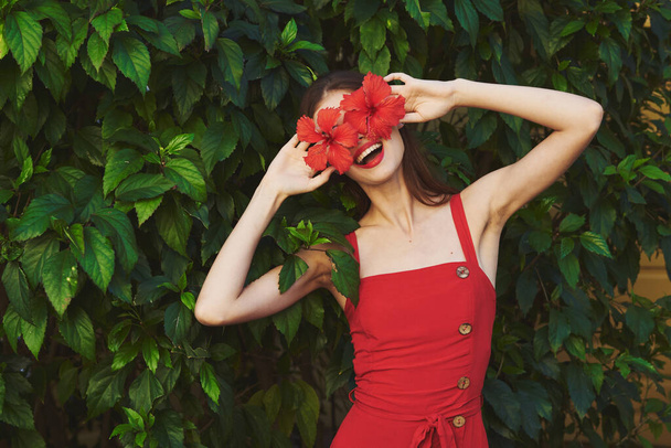  Young beautiful woman with red flowers in the garden                                 - Photo, Image