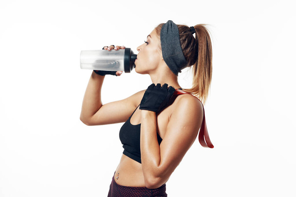 Studio shot. Young fit woman holding shaker, isolated  - Photo, Image