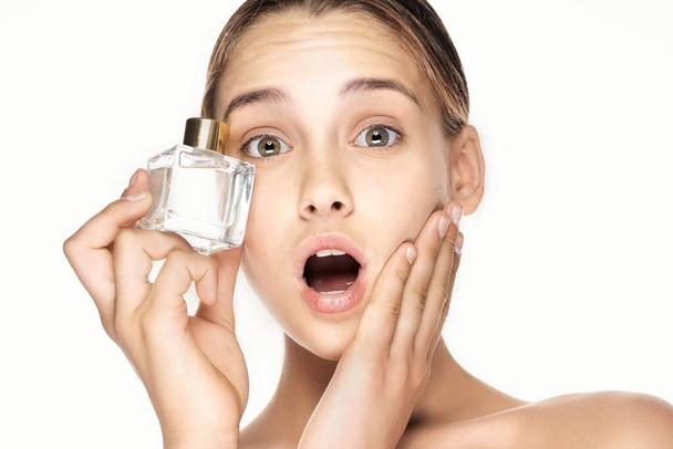 Retrato de jovem bela mulher surpreso com frasco de perfume isolado no fundo branco
 - Foto, Imagem
