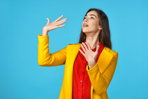 young beautiful woman in yellow jacket   posing in Studio with blue Background. - Foto, Bild