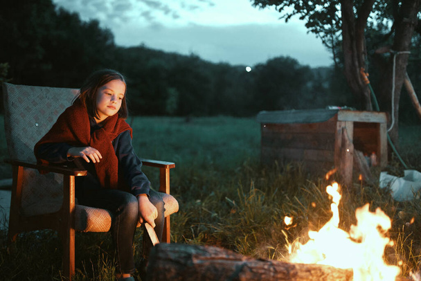 Güzel kız gece ateşin yanında oturuyor. - Fotoğraf, Görsel
