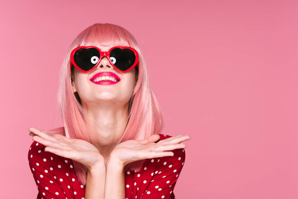 junge schöne Frau mit pinkfarbener Perücke und Sonnenbrille posiert im Studio  - Foto, Bild