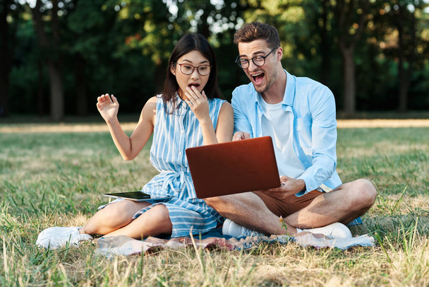 young students with laptop computer  and tablet  sitting on the lawn  - Photo, Image