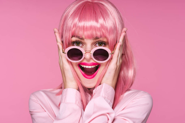 νεαρή όμορφη γυναίκα με ροζ περούκα και γυαλιά ηλίου ποζάρουν στο στούντιο  - Φωτογραφία, εικόνα