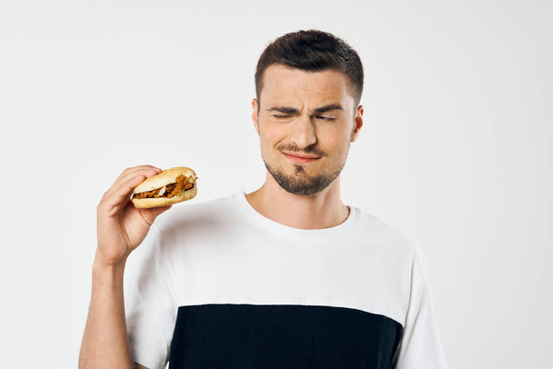 Young handsome man with hamburger in studio  - Foto, immagini