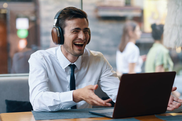 Młody biznesmen ze słuchawkami na laptopie w biurze  - Zdjęcie, obraz