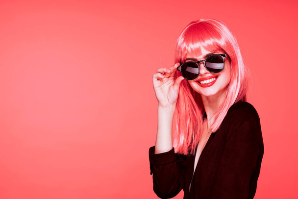 young beautiful woman in pink wig and sunglasses posing in studio  - Fotoğraf, Görsel