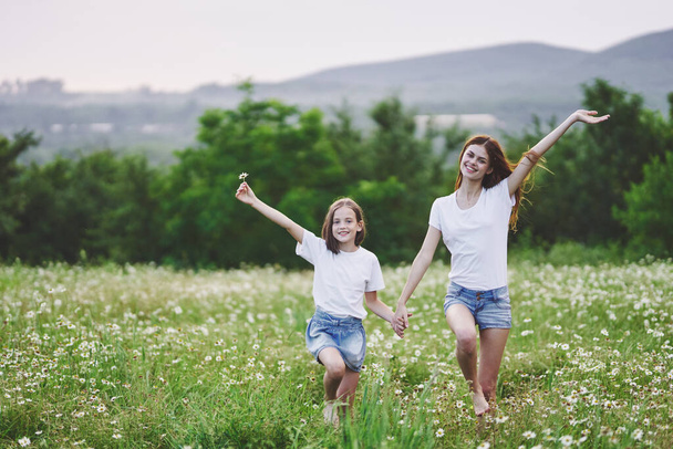 Young mother and her daughter having fun on camomile field - Photo, Image