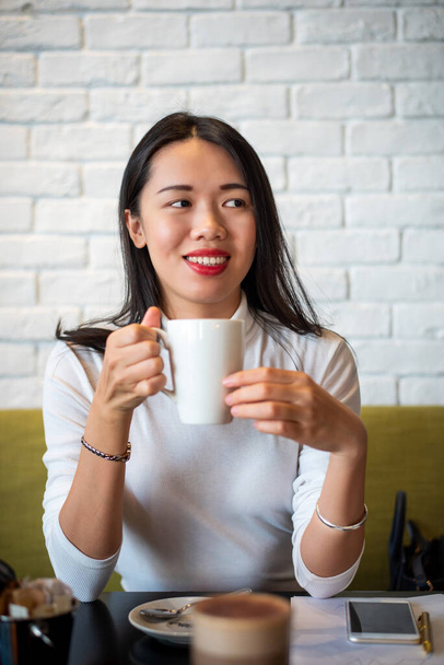 Azji kobieta mając filiżankę kawy w barze zbliżenie portret - Zdjęcie, obraz