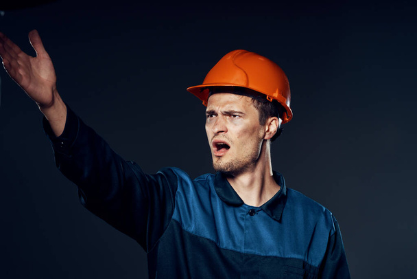 νεαρός θυμωμένος άντρας με στολή εργασίας και κράνος. Φωτογραφία στούντιο - Φωτογραφία, εικόνα
