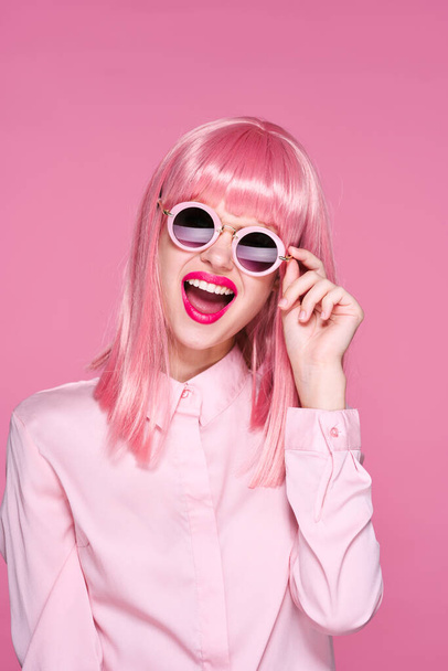 young beautiful woman in pink wig and sunglasses posing in studio  - 写真・画像