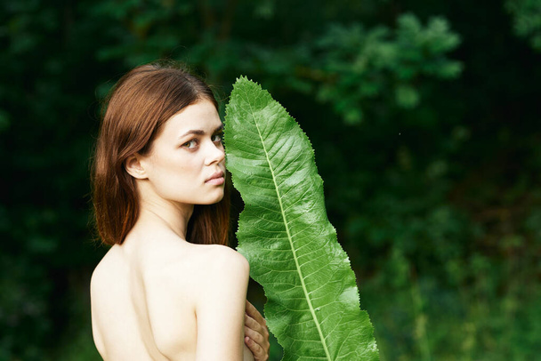 Junge schöne Frau posiert mit grünem Blatt im Garten - Foto, Bild