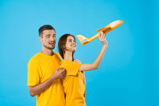 Nuori kaunis pari leikkii keltainen lelu kone sinisellä taustalla  - Valokuva, kuva
