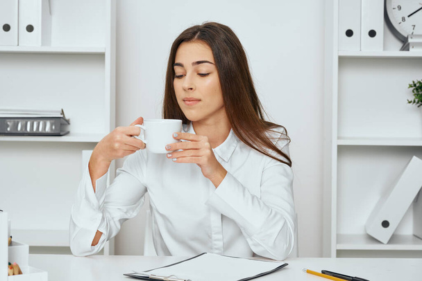 giovane bella donna d'affari seduta alla scrivania in ufficio con tazza - Foto, immagini