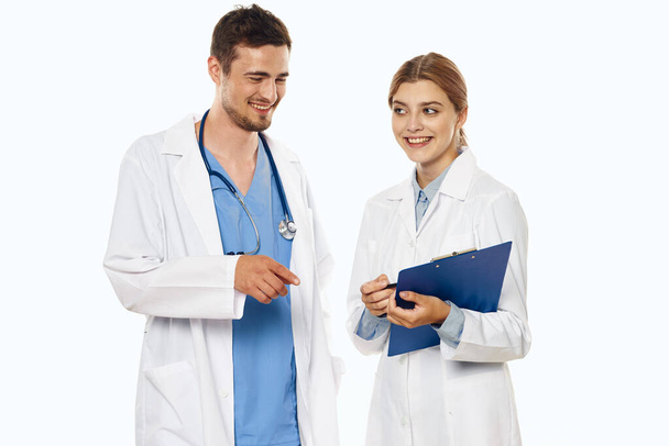 Giovane medico e infermiera sorridente in studio, sfondo isolato.  - Foto, immagini