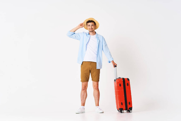 Young man with red suitcase in studio - Foto, imagen