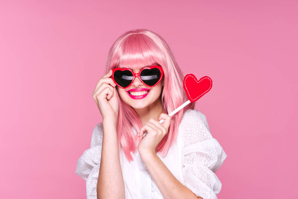Young woman in pink wig holding heart  on pink background - Zdjęcie, obraz