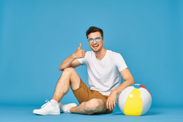 Young man playing with ball in studio showing thumb up - Foto, imagen