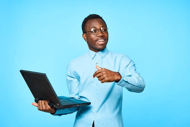Giovane africano sorpreso uomo d'affari in possesso di laptop isolato su sfondo blu - Foto, immagini