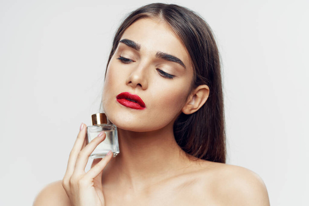 Young beautiful woman holding perfume bottle in studio - Fotó, kép