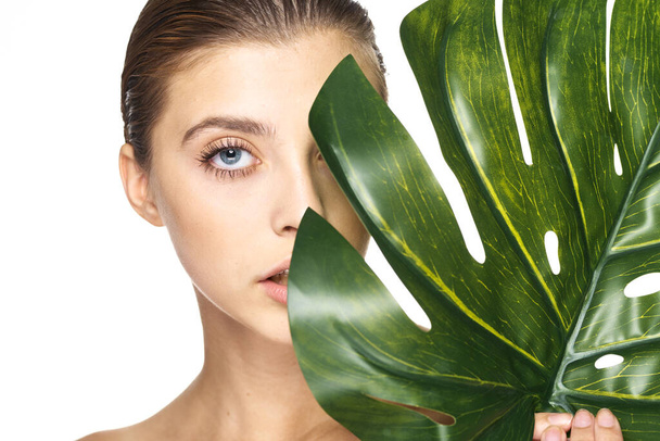Young beautiful model posing with leaf in studio - Photo, Image