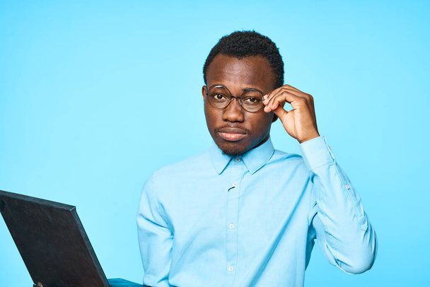 Young african businessman holding laptop isolated on blue background - Fotografie, Obrázek