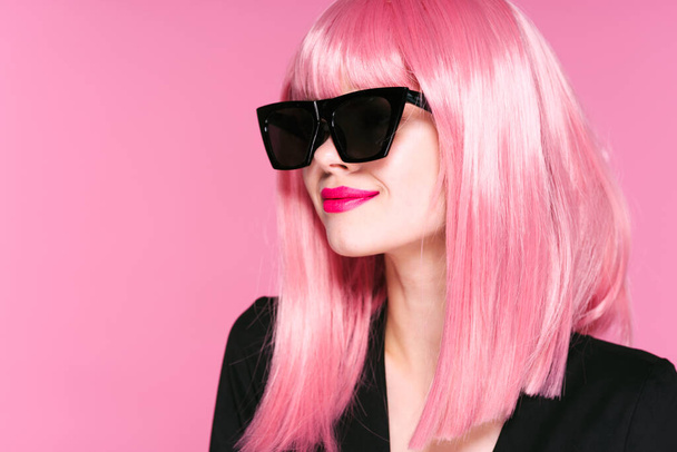 young beautiful woman in pink wig and sunglasses posing in studio  - Foto, afbeelding