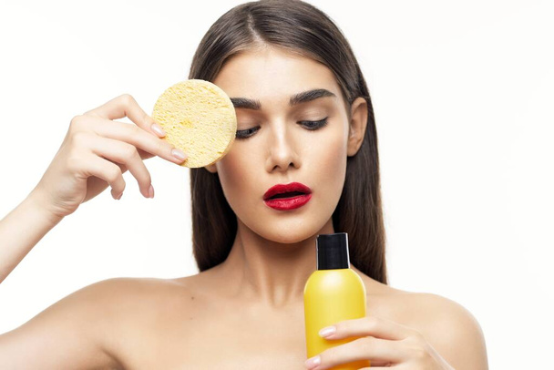 Young beautiful woman cleaning her face with sponge. Beauty routine. Studio shot - Foto, afbeelding