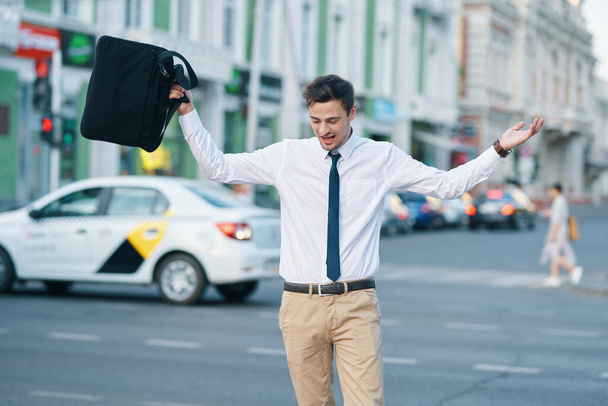 Jonge knappe zakenman loopt op straat  - Foto, afbeelding