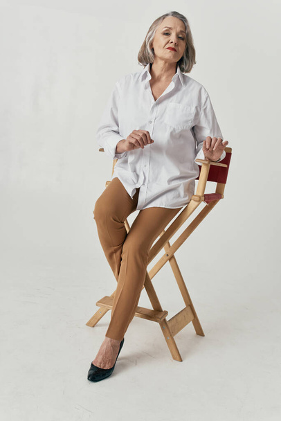 Beautiful senior woman on chair    in studio - Φωτογραφία, εικόνα