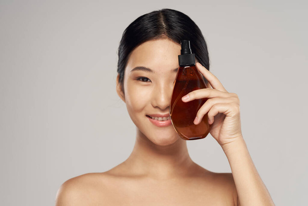 Young asian woman with hair spray in studio. Beauty, fashion photography - Фото, зображення